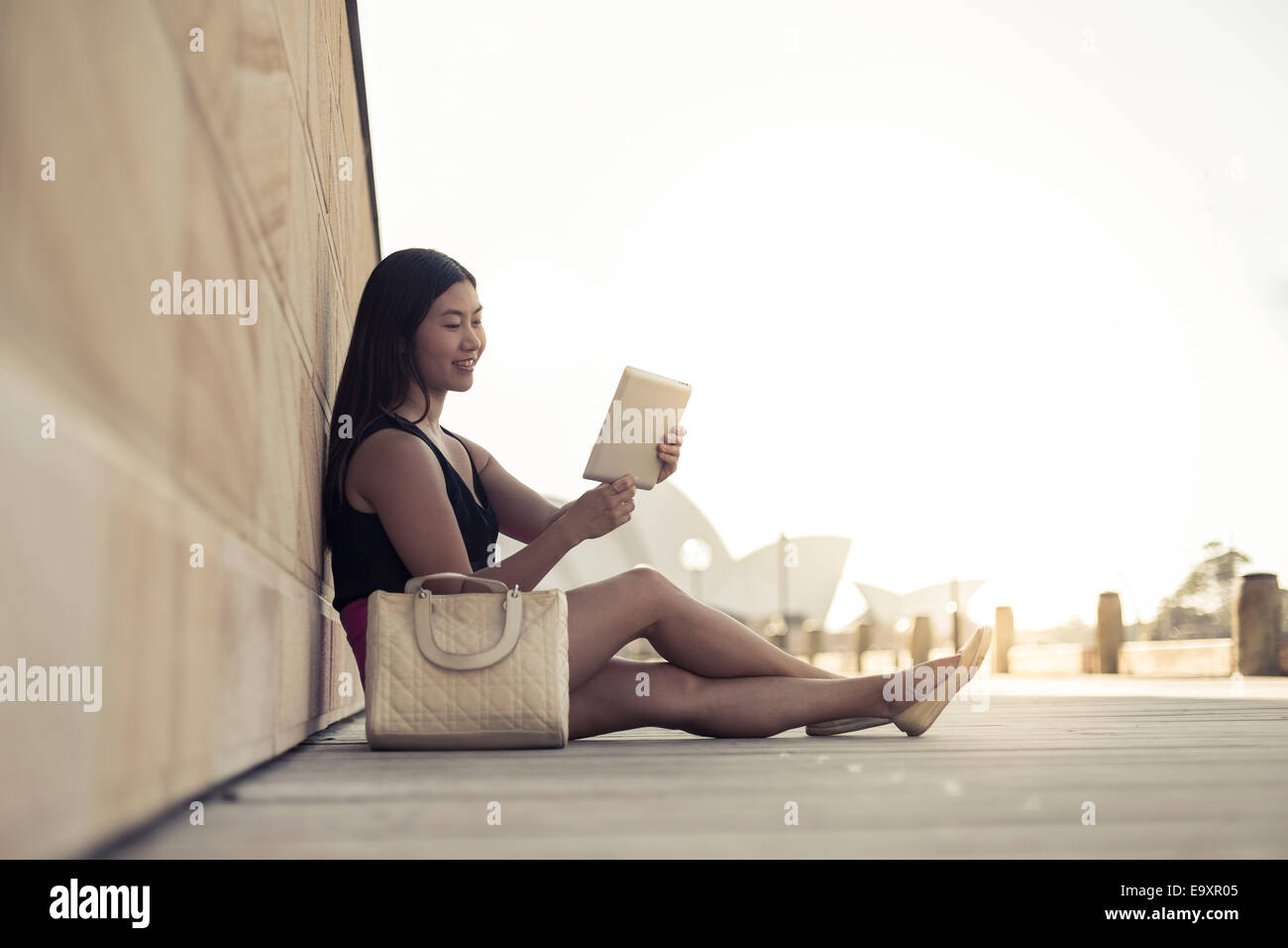 A young woman relaxing whilst looking at content on a tablet device Stock Photo