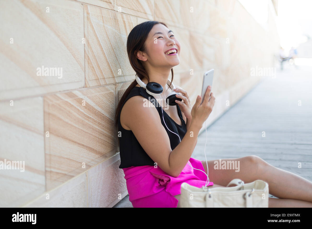 A young woman relaxing using a smartphone with headphones Stock Photo