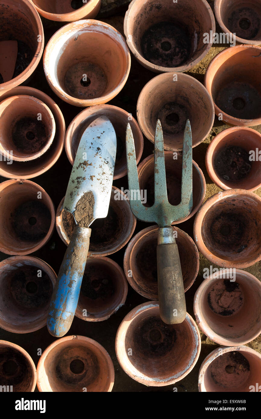 Garden hand trowel and fork on old terracotta flower pots Stock Photo