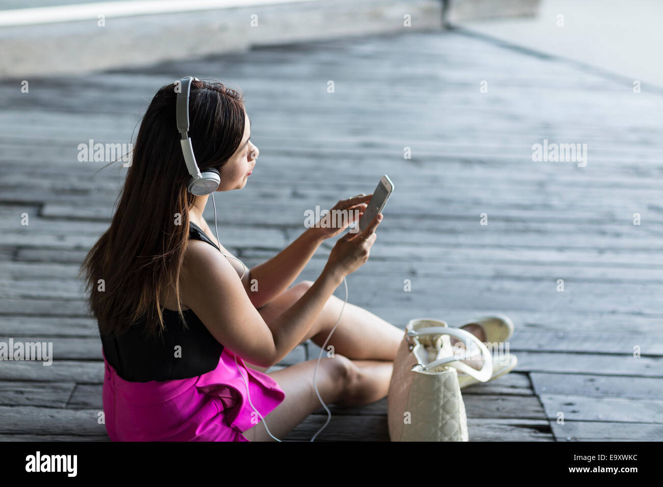 A young Asian woman consuming content on her smartphone outdoors Stock Photo