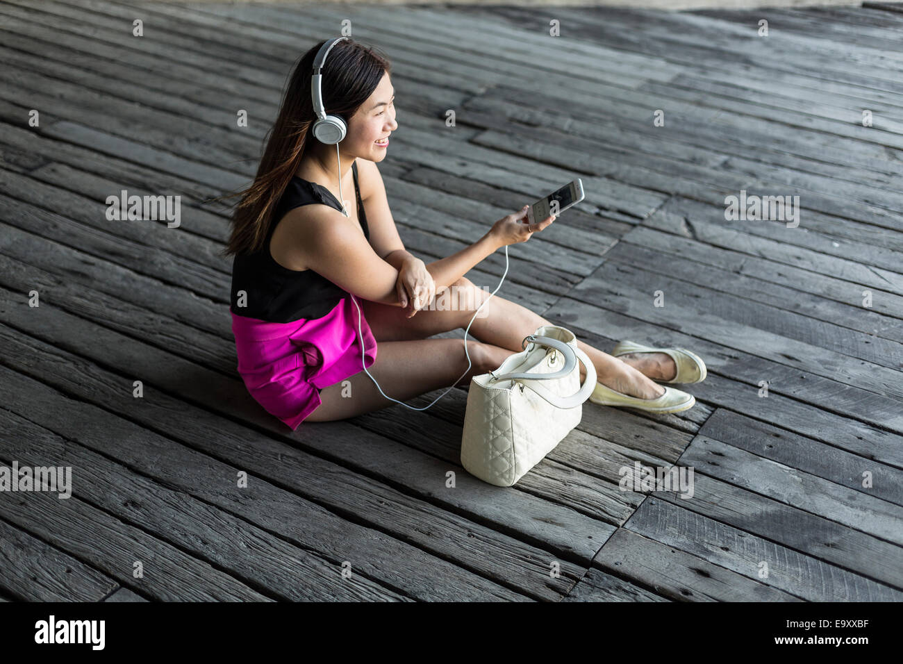 A young Asian woman consuming content on her smartphone outdoors Stock Photo