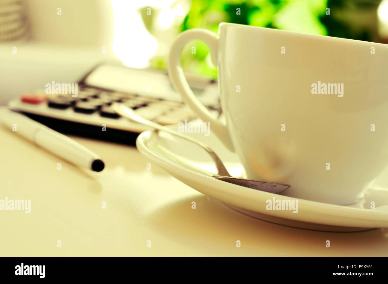 detail of a desk with a calculator and a cup of coffee or tea in an office with a nice atmosphere Stock Photo