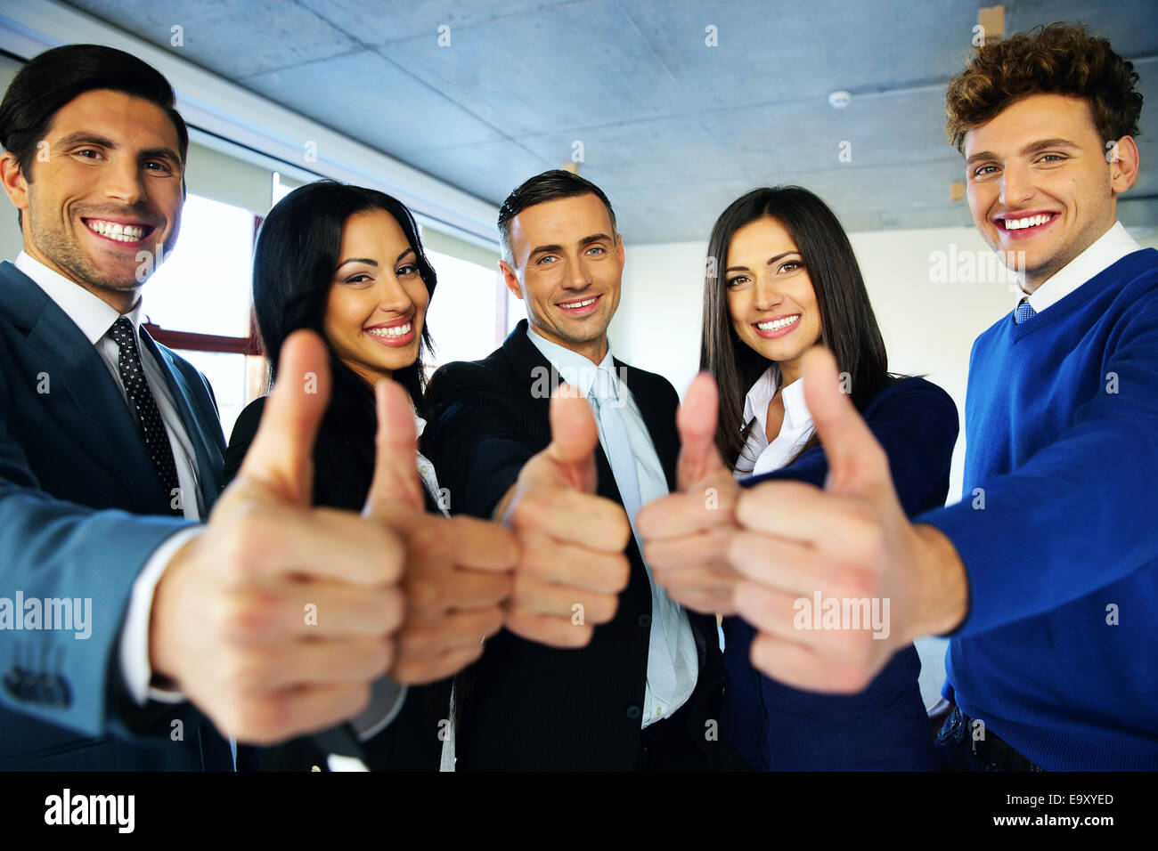 Portrait of happy young business people with thumbs up sign Stock Photo ...