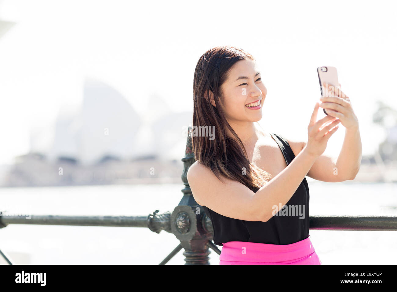 A young Asian woman using her mobile device to take a 'selfie' Stock Photo