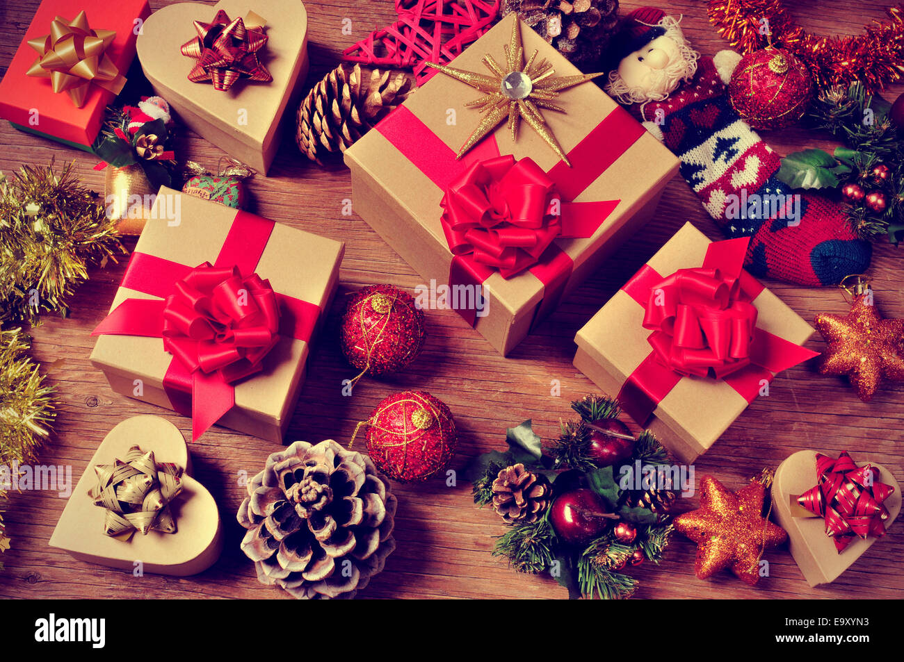 a pile of gifts and christmas ornaments, such as christmas balls, stars and tinsel, on a rustic wooden table Stock Photo