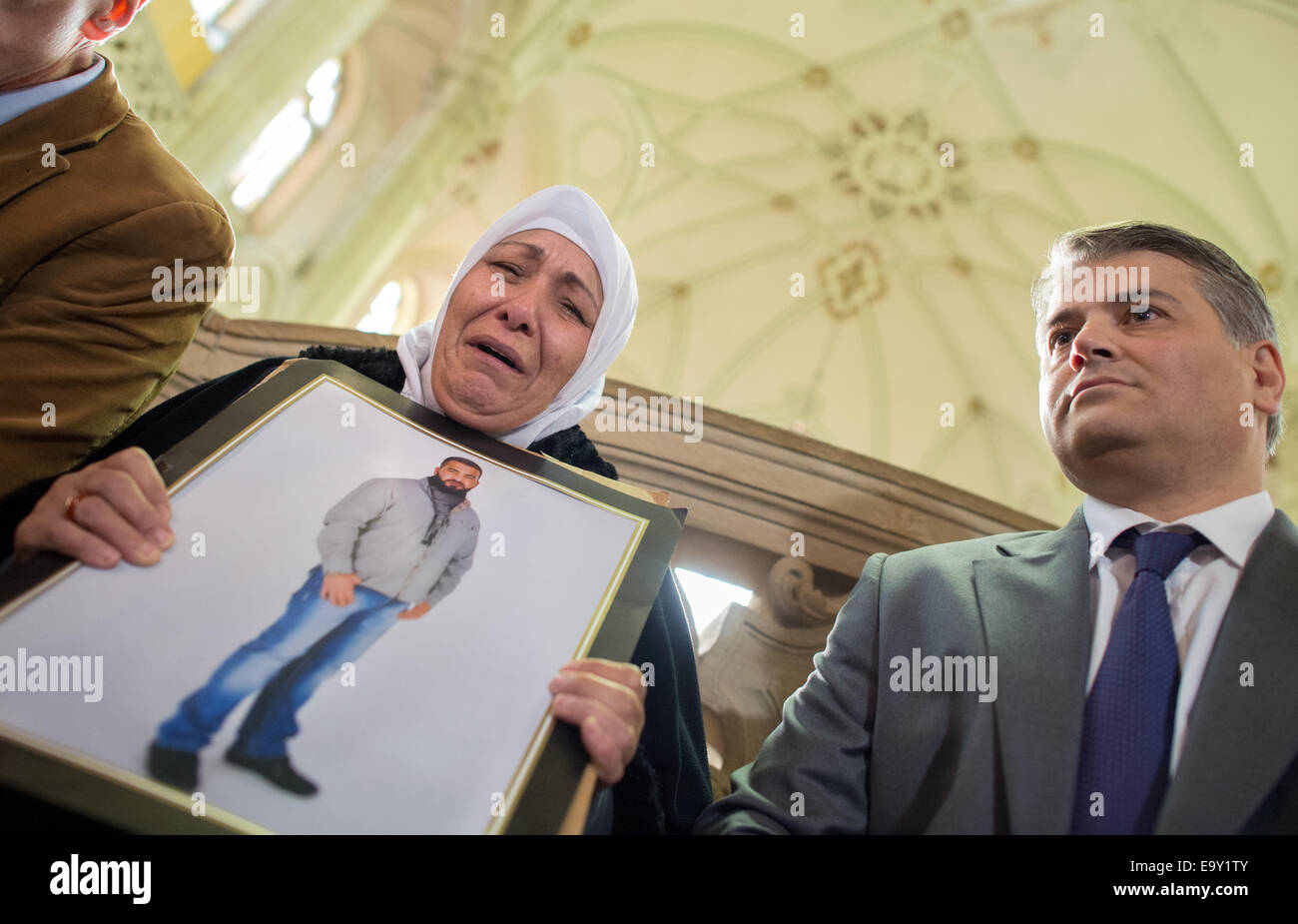 Berlin-Moabit, Germany. 04th Nov, 2014. Mother of murder victim Semiya O., accompanied by her lawyers Mehmet Daimaguler (R), holds a picture of her murdered son outside of the courtroom at the criminal court in Berlin-Moabit, Germany, 04 November 2014. The trial starts on Tuesday against eleven bikers who are charged with killing a 26 year-old man in a betting agents in Berlin in January. Photo: MATTHIAS BALK/dpa/Alamy Live News Stock Photo