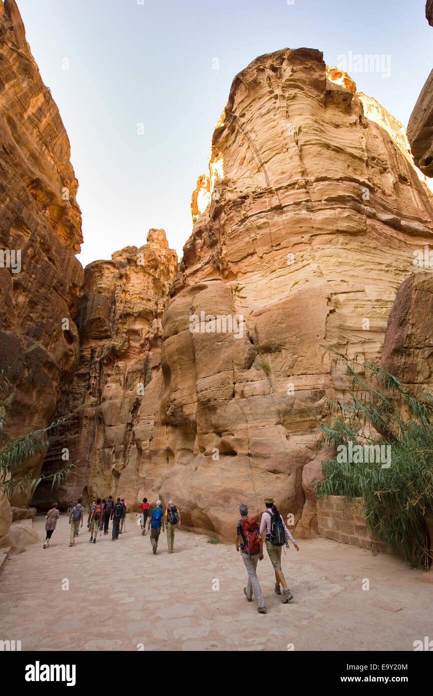 Tourists are walking through 'the Siq'.'The Siq' is a narrow gorge who leads visitors into Petra in Jordan Stock Photo