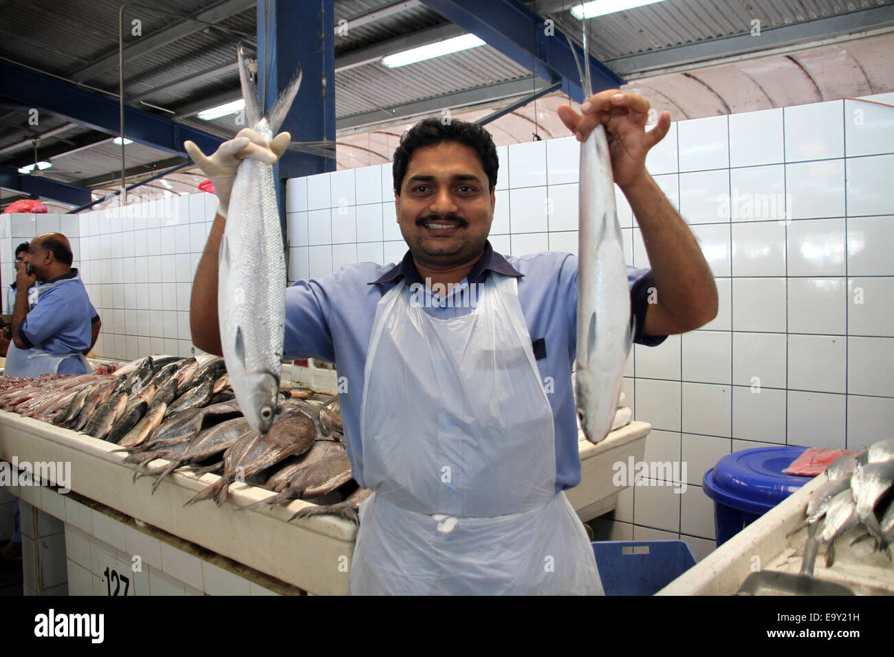 A market trader holds up two fish in the Deira fish market in Dubai
