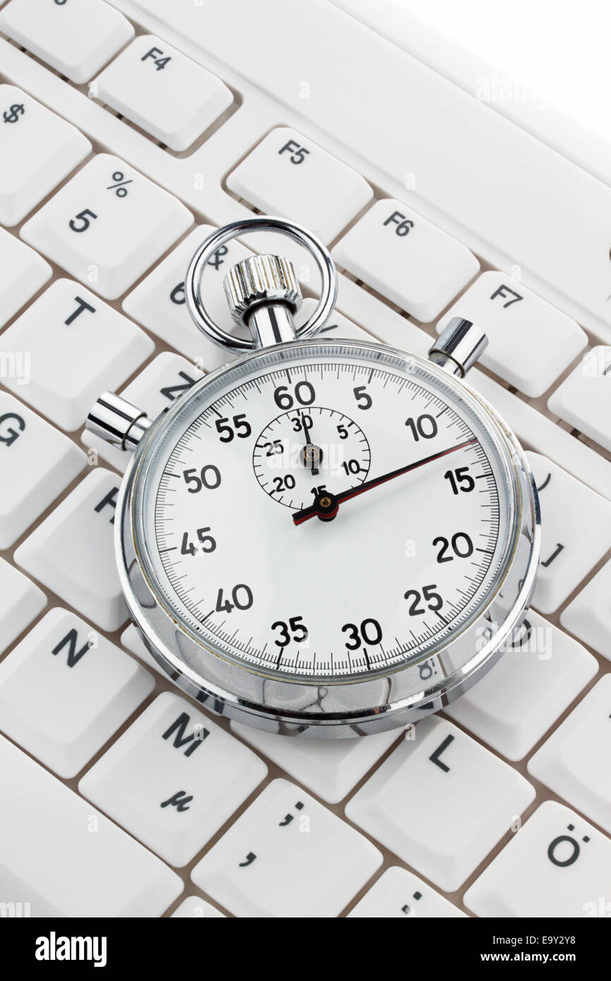 A stopwatch lies on a computer keyboard. Working time is money Stock Photo