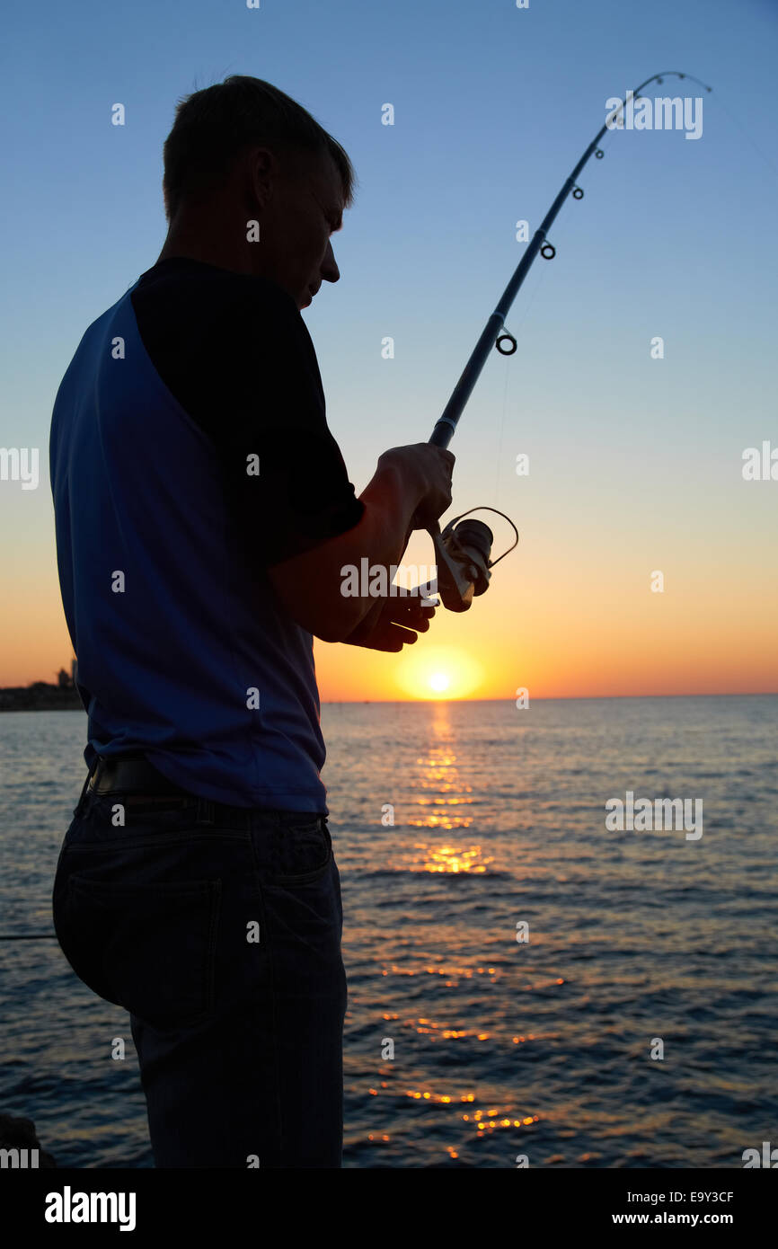 Fisherman fishes on the lake. Silhouette at sunset Stock Photo - Alamy