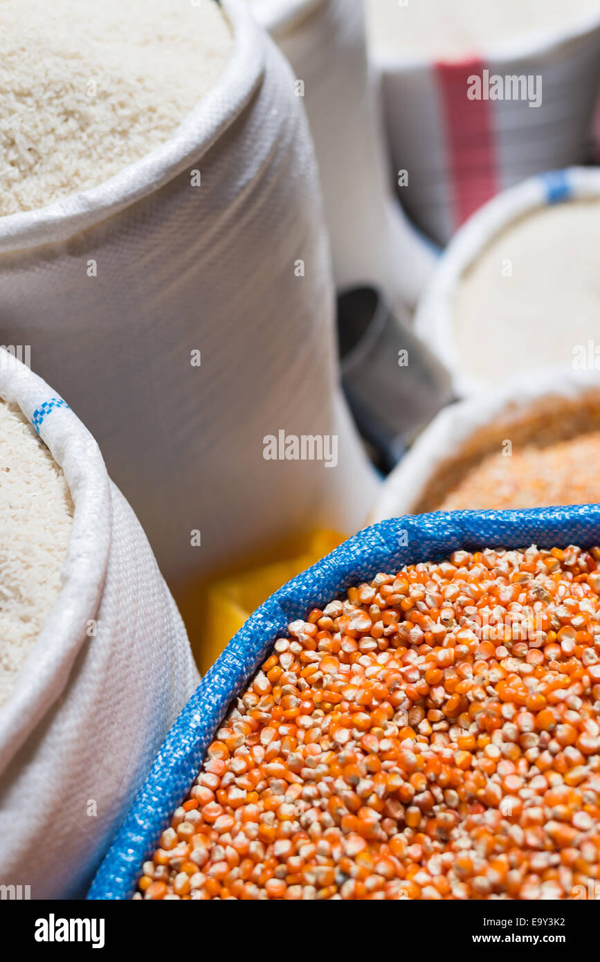 Bag of  yellow - orange corn for sell in south east asian market with sacks of white rise in the background. Selective focus. Stock Photo