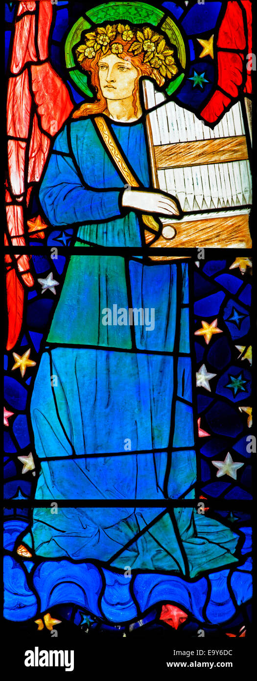 Stained glass depicting a red-winged angel playing a hand organ, by William Morris, Staveley Church, Lake District, Cumbria, UK Stock Photo
