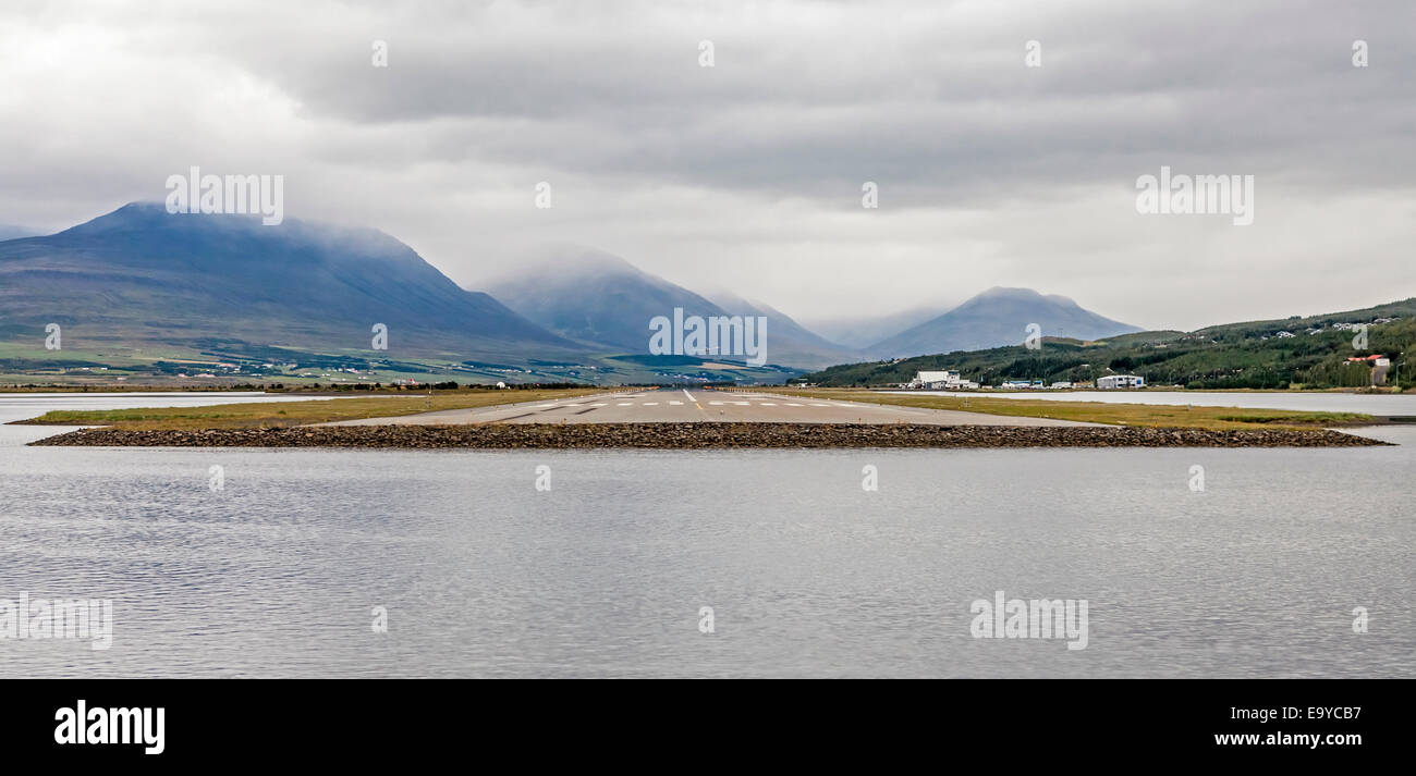 View from the end of runway at Akureyri airport in Iceland. A small plane is taking off. Stock Photo