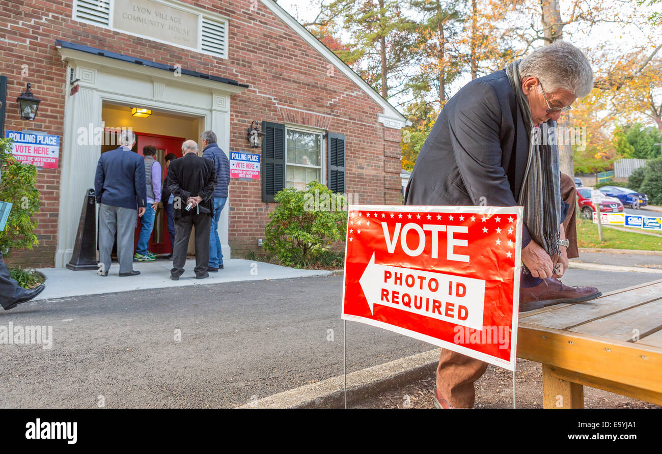 Arlington, Virginia, USA. 4th November, 2014. Man tying shoe laces, and eople at polling place for voting November 4, 2014. Photo ID required sign. New voter ID law in Virginia. Credit:  Rob Crandall/Alamy Live News Stock Photo