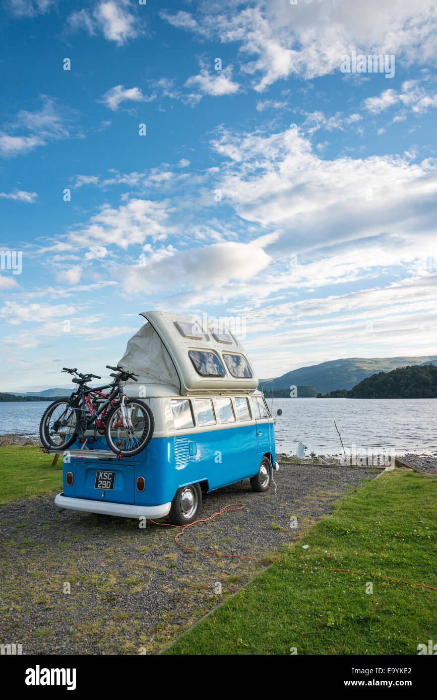A blue VW campervan or vw camper parked on the shore of Loch Lomond Scotland UK in summer Stock Photo