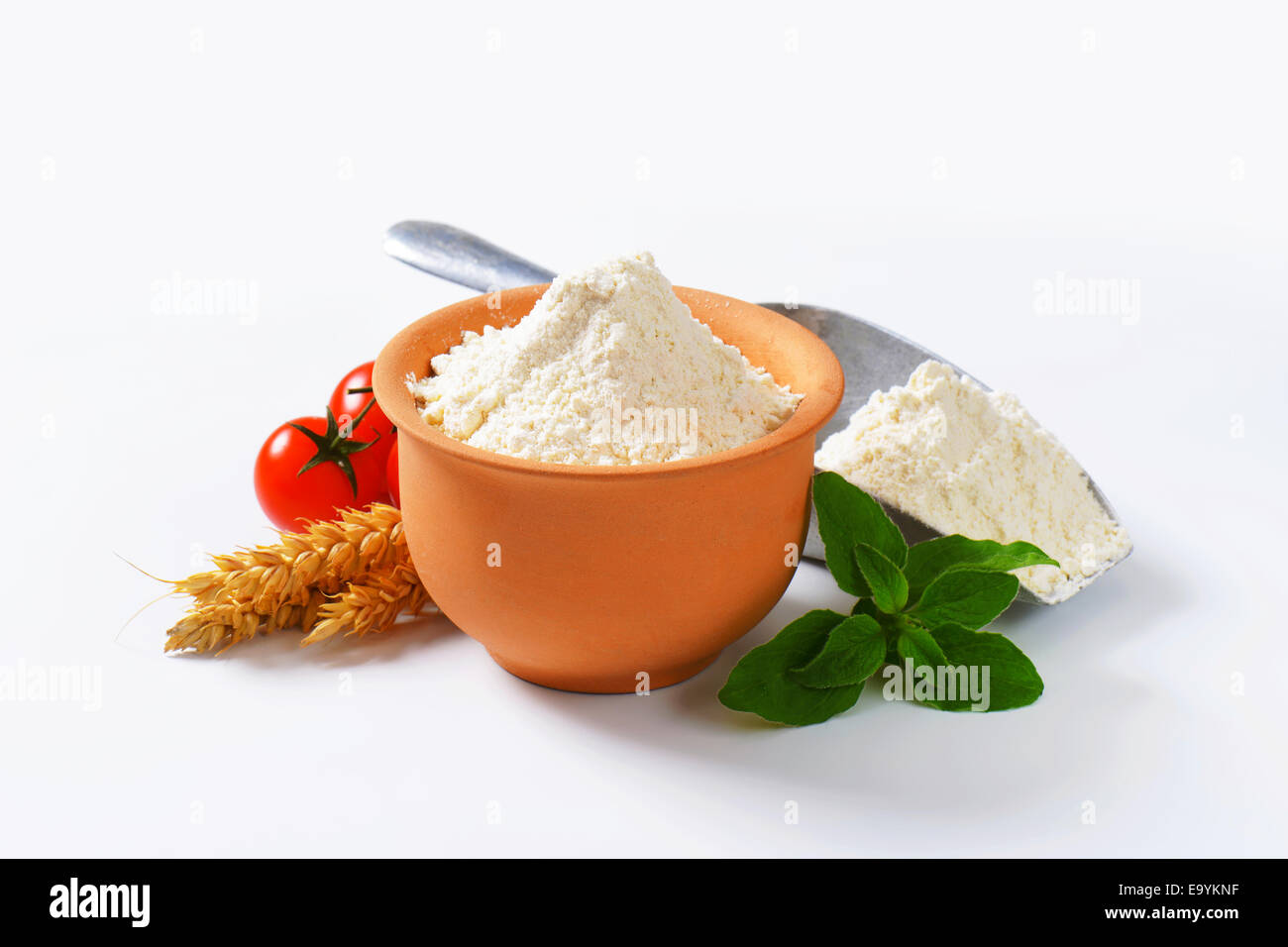 Finely ground flour in terracotta bowl and metal scoop Stock Photo