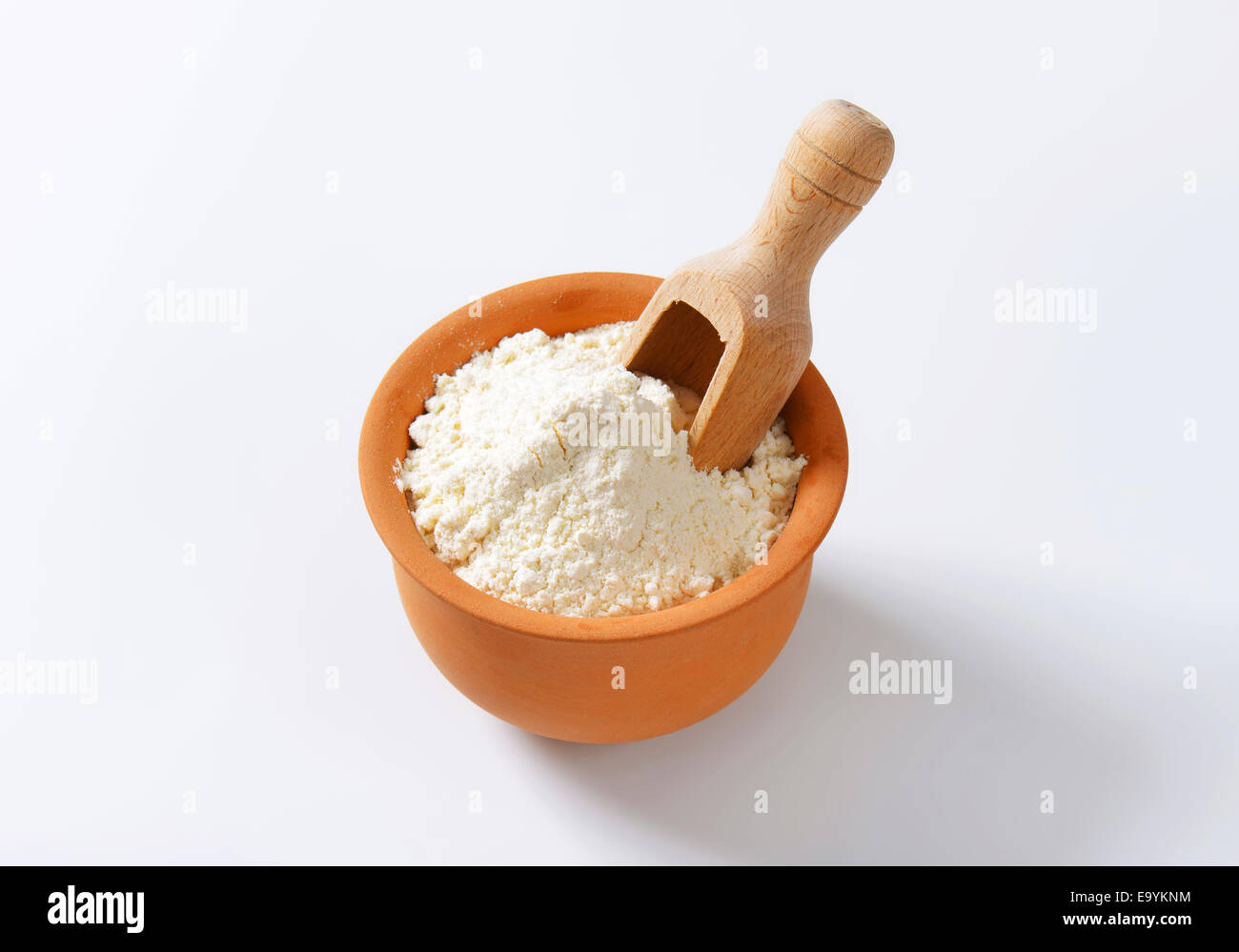 Finely ground flour and wooden scoop in terracotta bowl Stock Photo