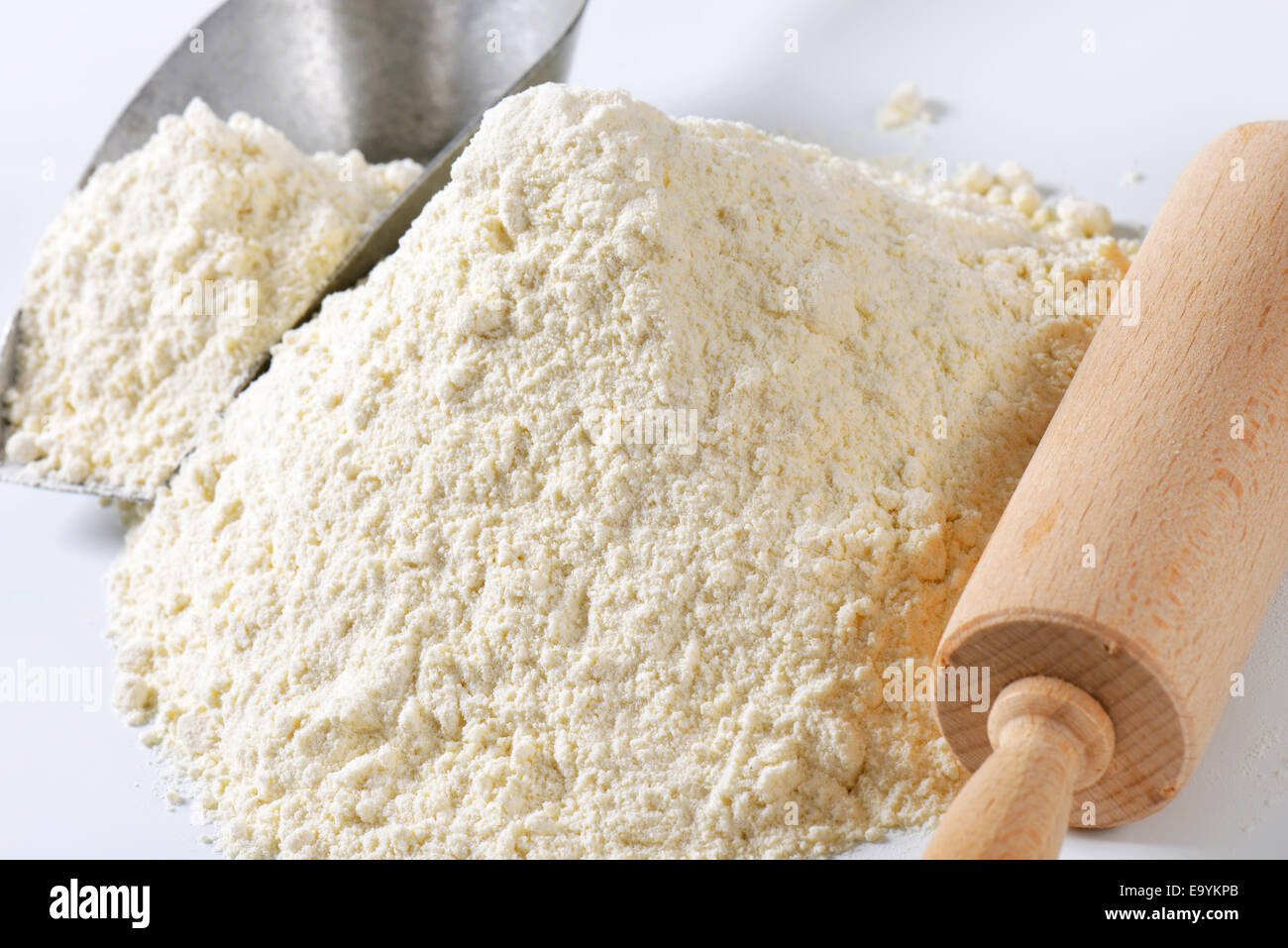 Pile of finely ground flour, wood rolling pin and metal scoop Stock Photo