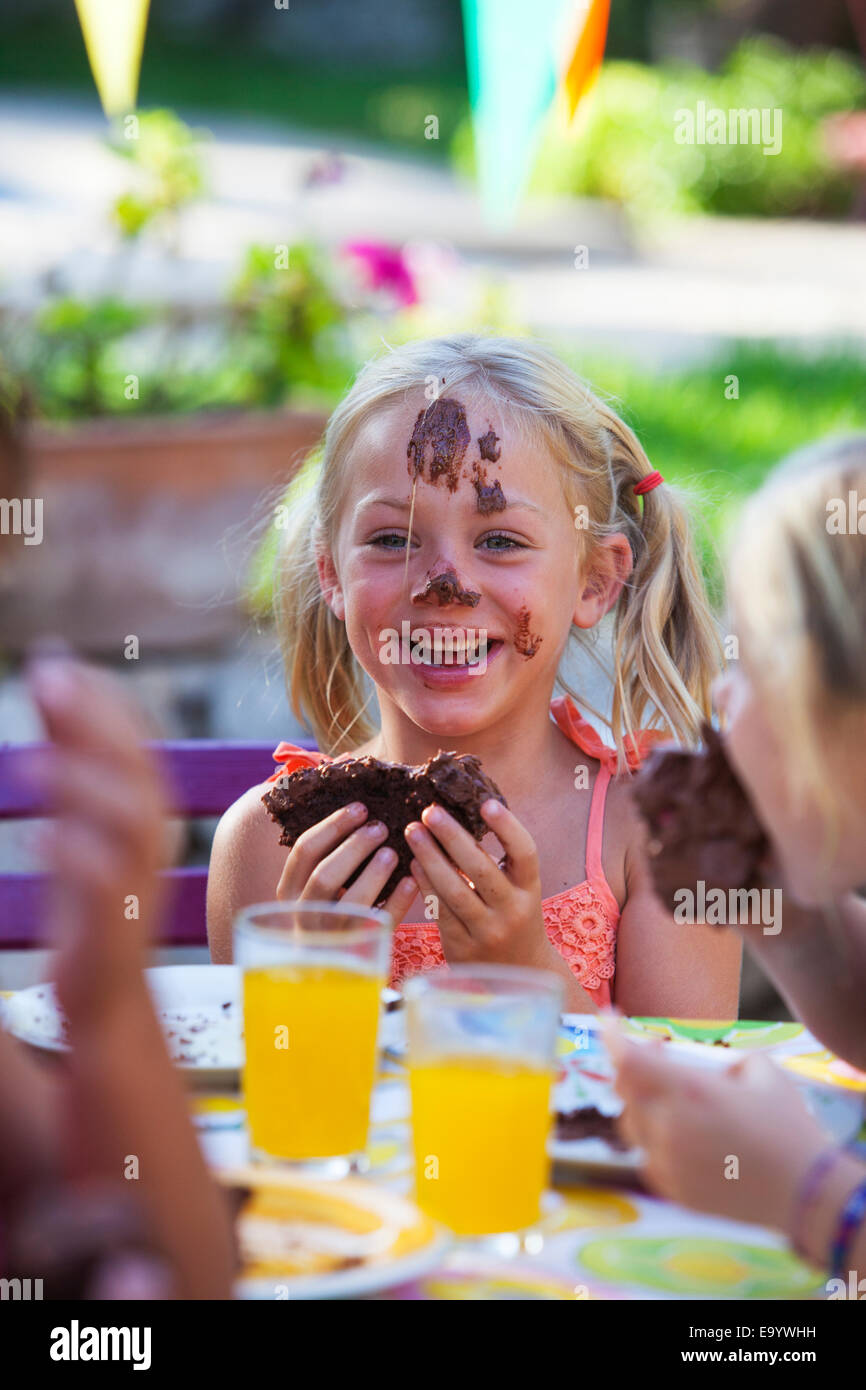 Girl eating chocolate cake, face covered in icing Stock Photo