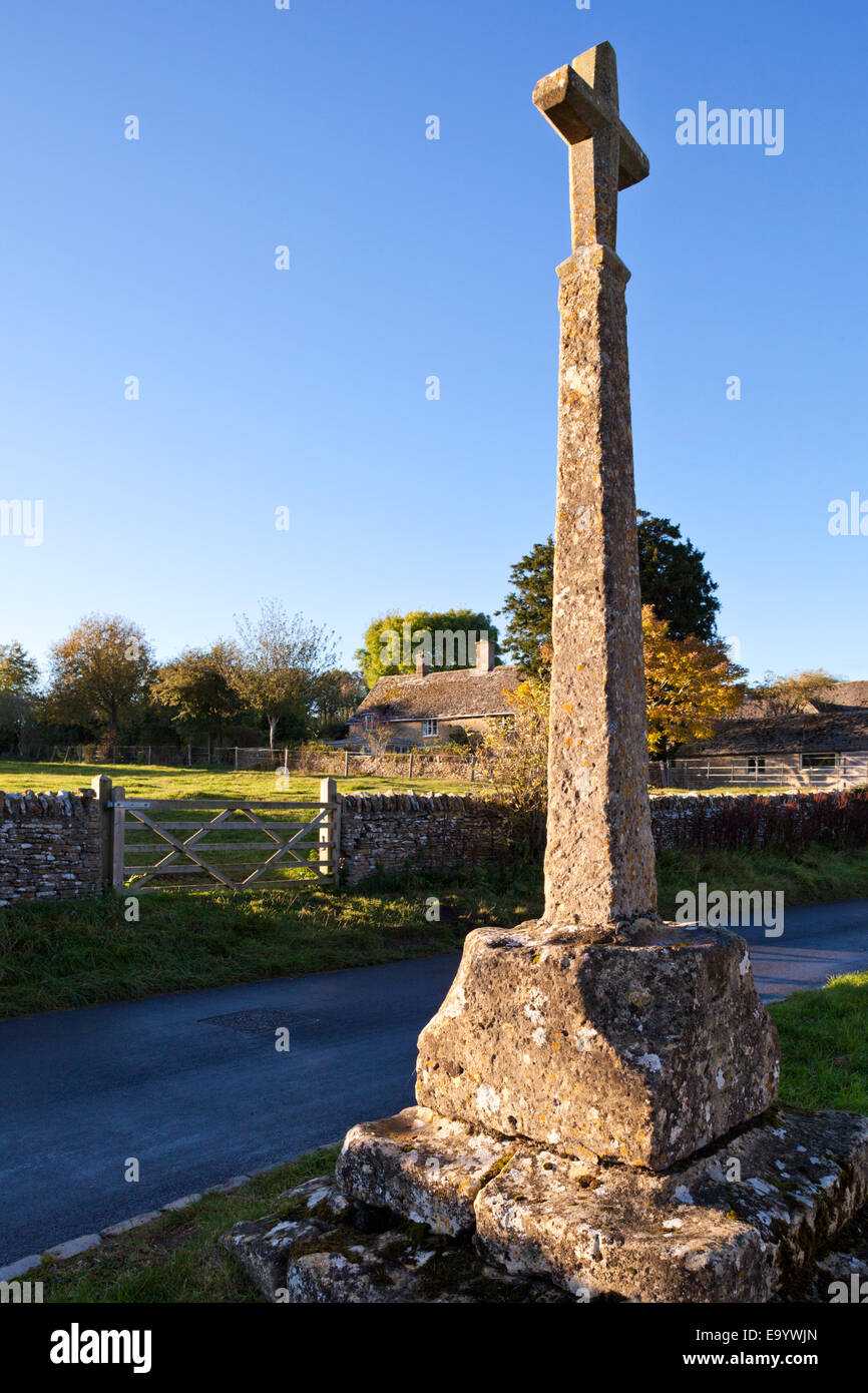 The last of the evening sunlight falling on the 14th century wayside cross in the Cotswold village of Condicote, Gloucestershire Stock Photo