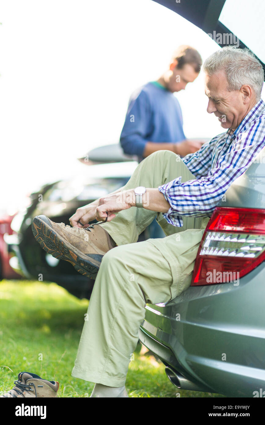 Man sitting on car boot tying shoelaces Stock Photo Alamy