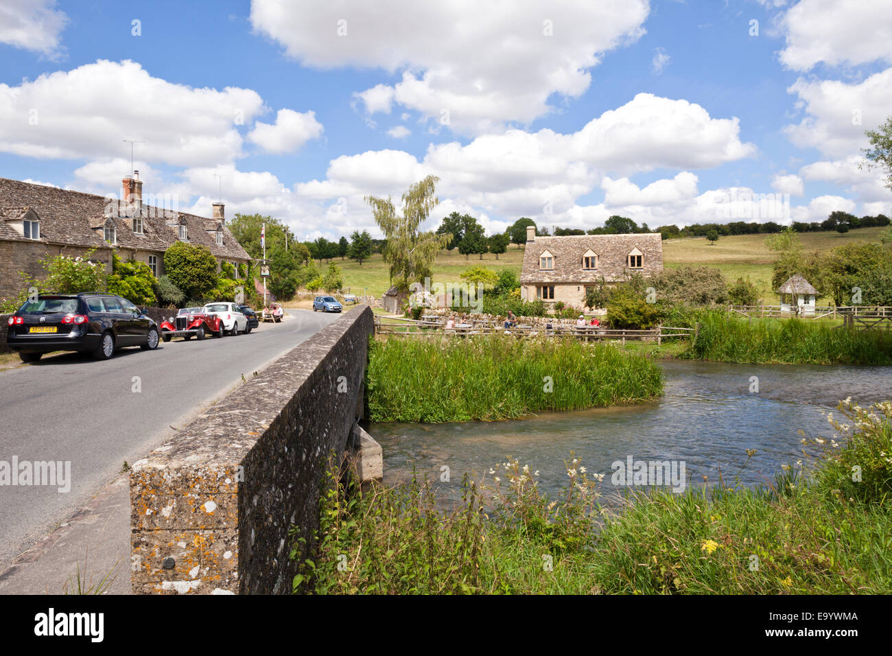 The Swan Inn on the banks of the River Windrush in the Cotswold village of Swinbrook, Oxfordshire UK Stock Photo