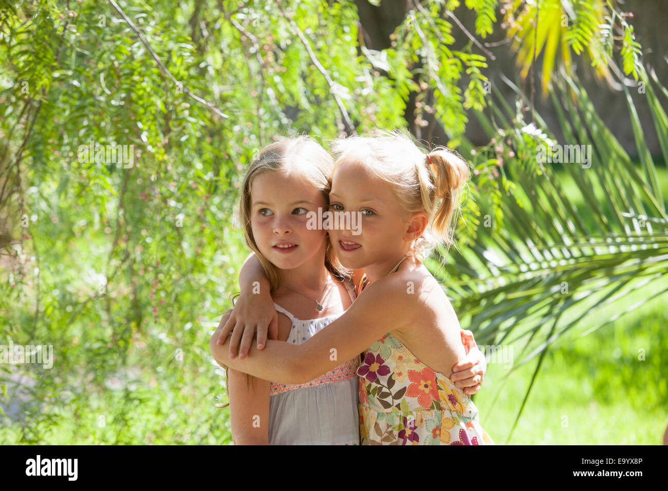 Candid portrait of two girls with arms around each other in garden Stock Photo