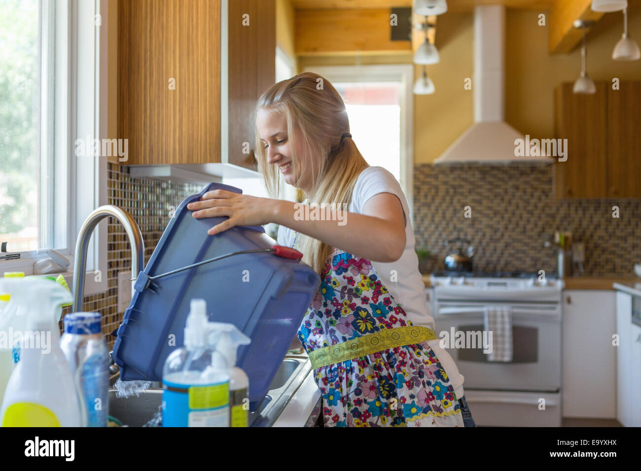 Young woman cleaning kitchen with green cleaning products Stock Photo