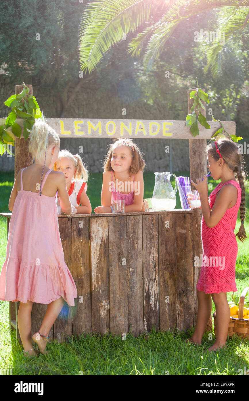 Four girls buying and selling at lemonade stand in park Stock Photo