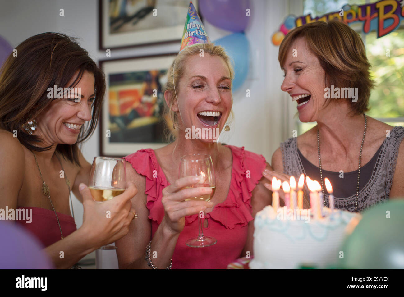 Three mature women at birthday party, laughing Stock Photo