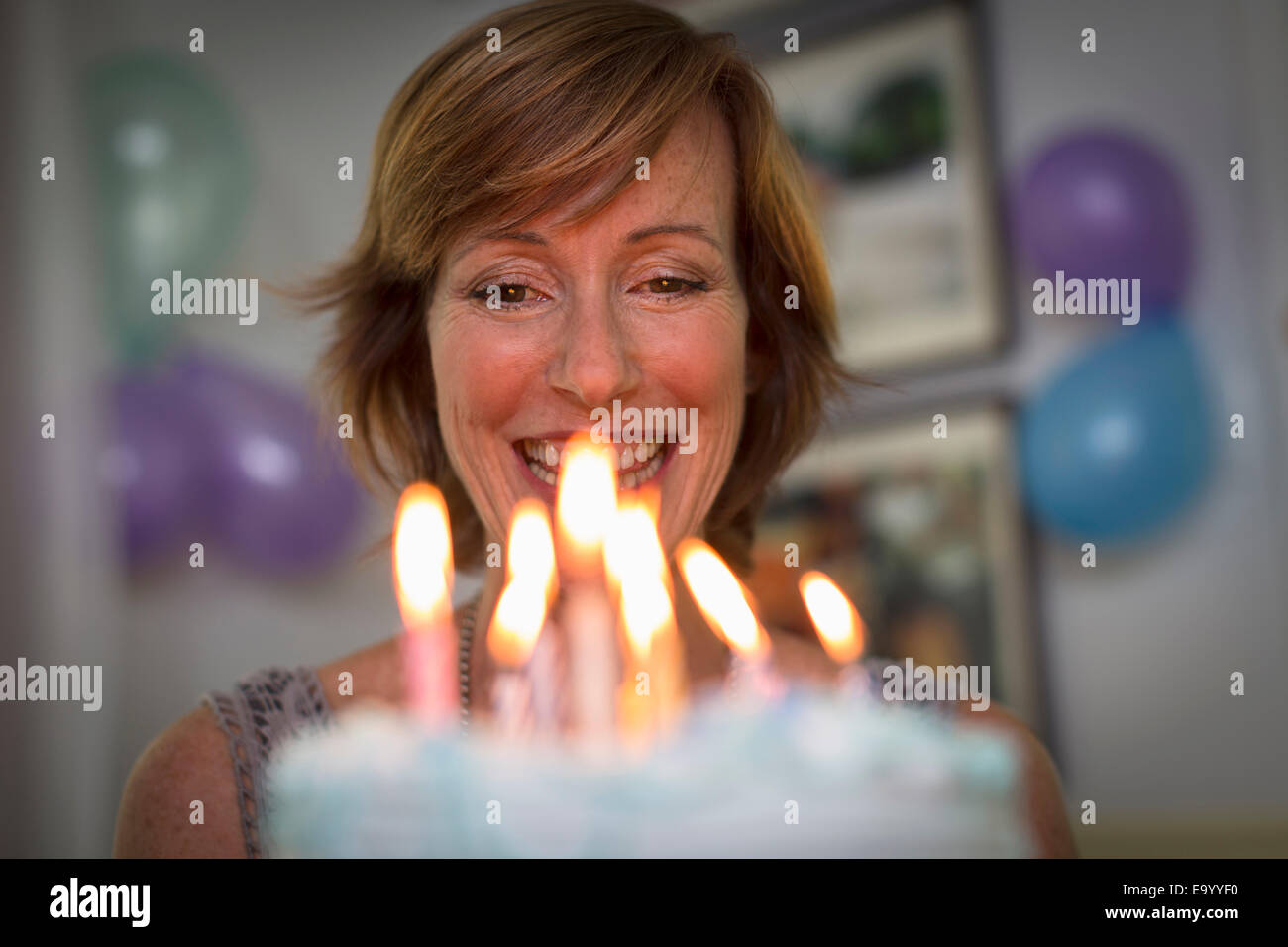 Mature woman holding birthday cake with candles Stock Photo