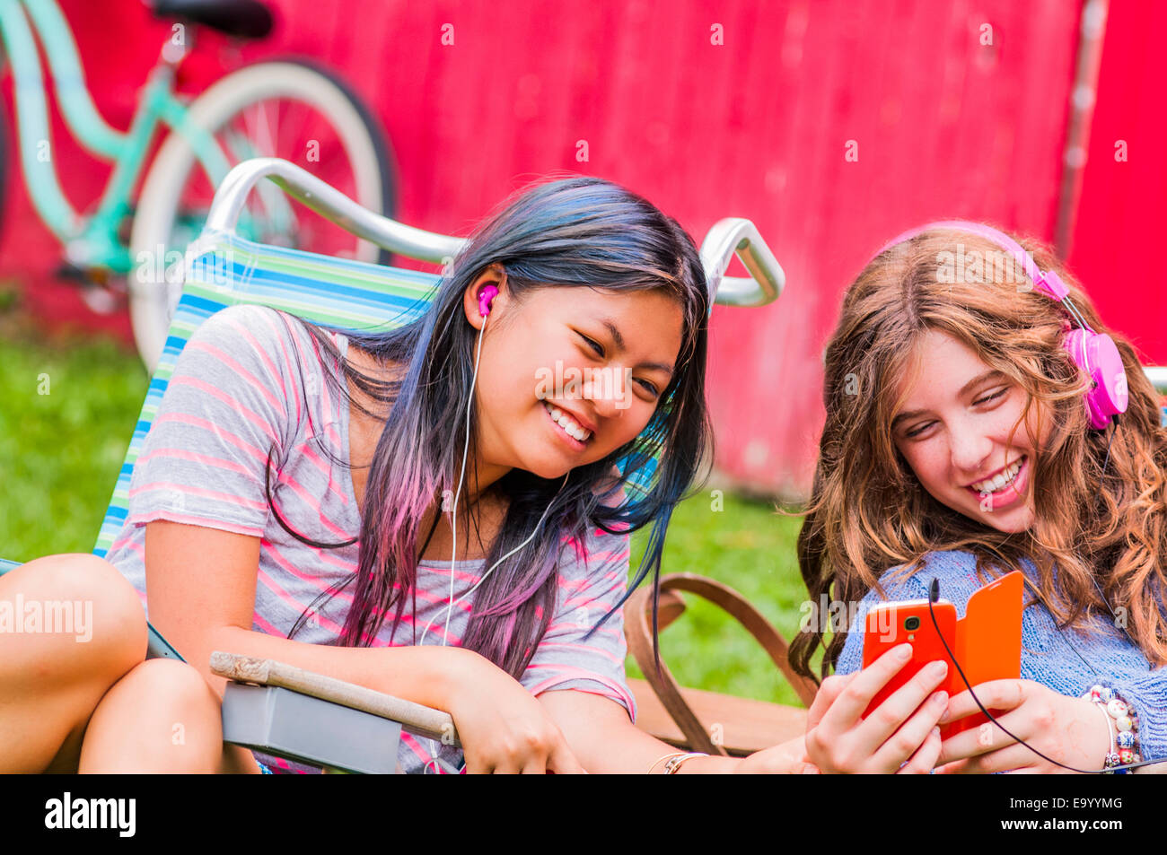 Two teenagers wearing headphones, listening to music, outdoors Stock Photo