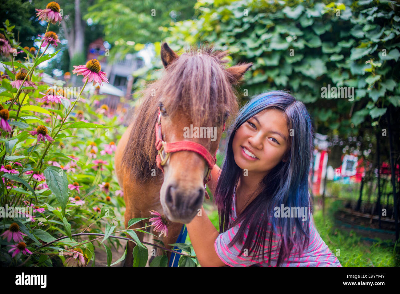 Portrait of teenage girl standing with pony, outdoors Stock Photo