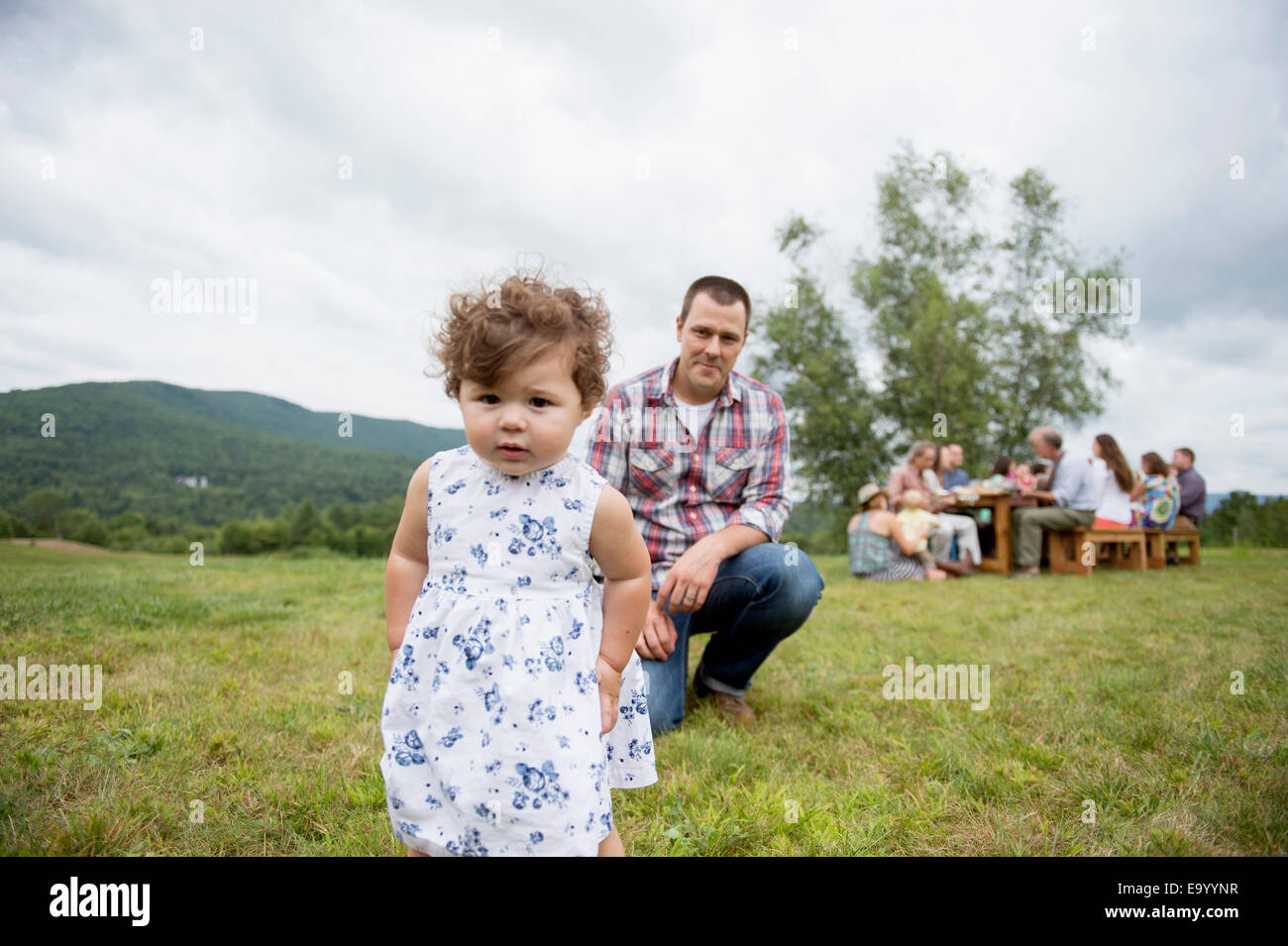 Father playing with daughter at family gathering, outdoors Stock Photo