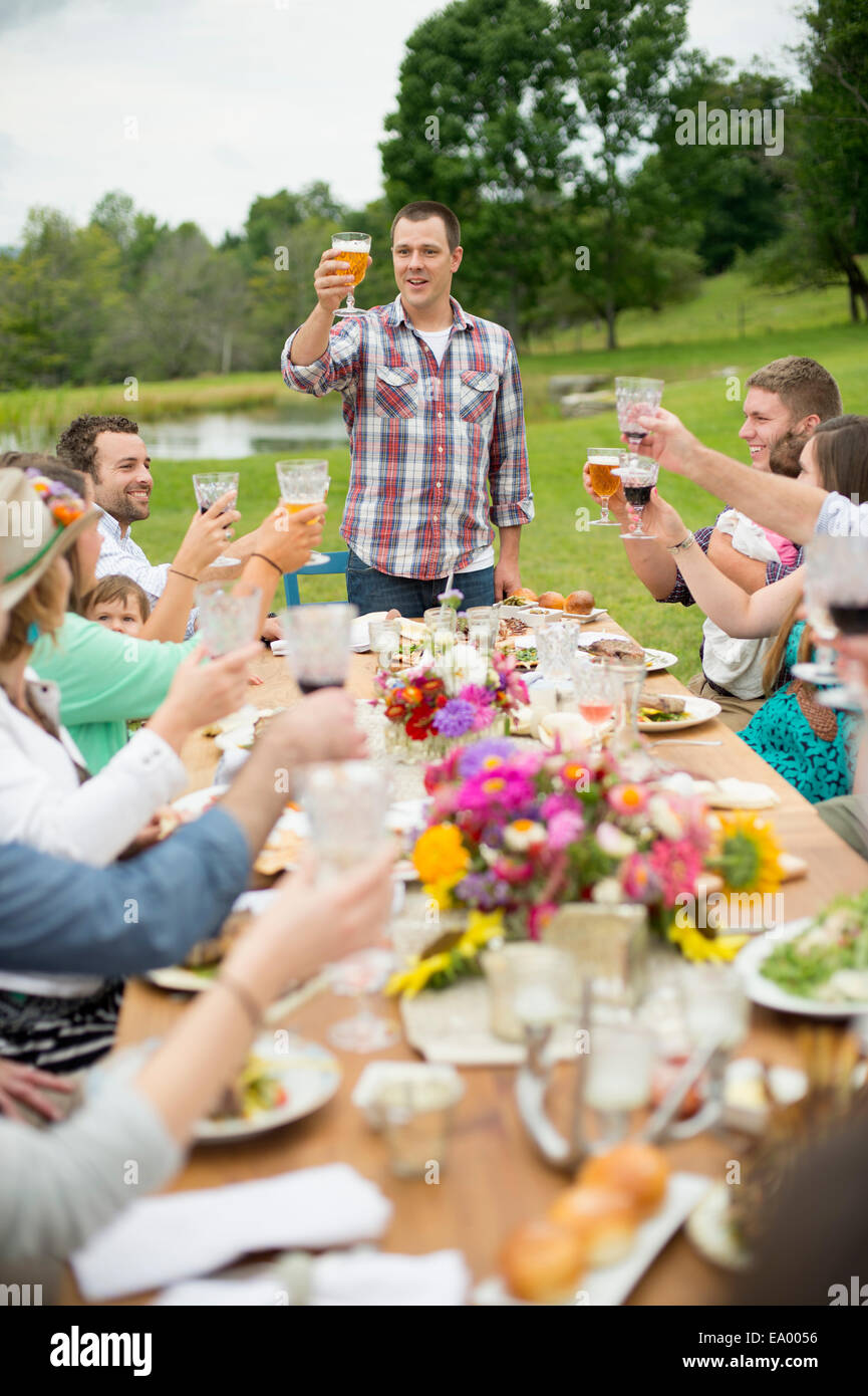 Family and friends making a toast at outdoor meal Stock Photo