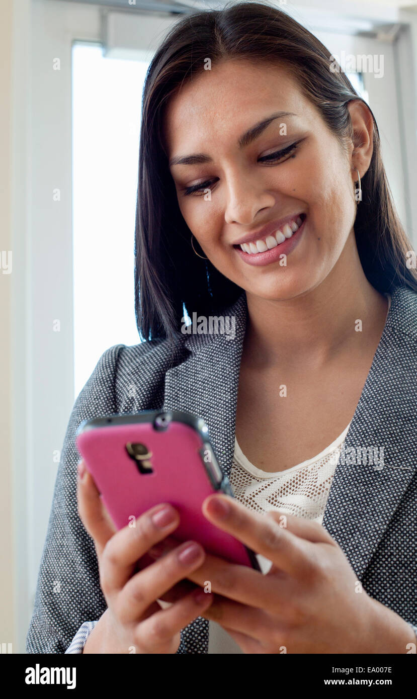 Young businesswoman woman looking at texts on smartphone in office Stock Photo