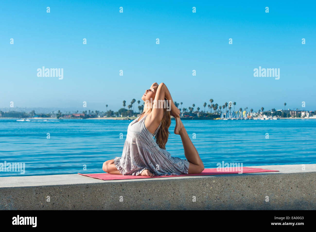 Young woman practicing yoga position on pier at Pacific beach, San Diego, California, USA Stock Photo