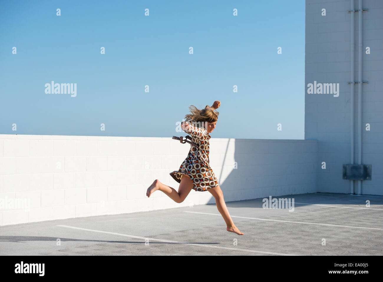 Girl jumping barefoot on building rooftop Stock Photo