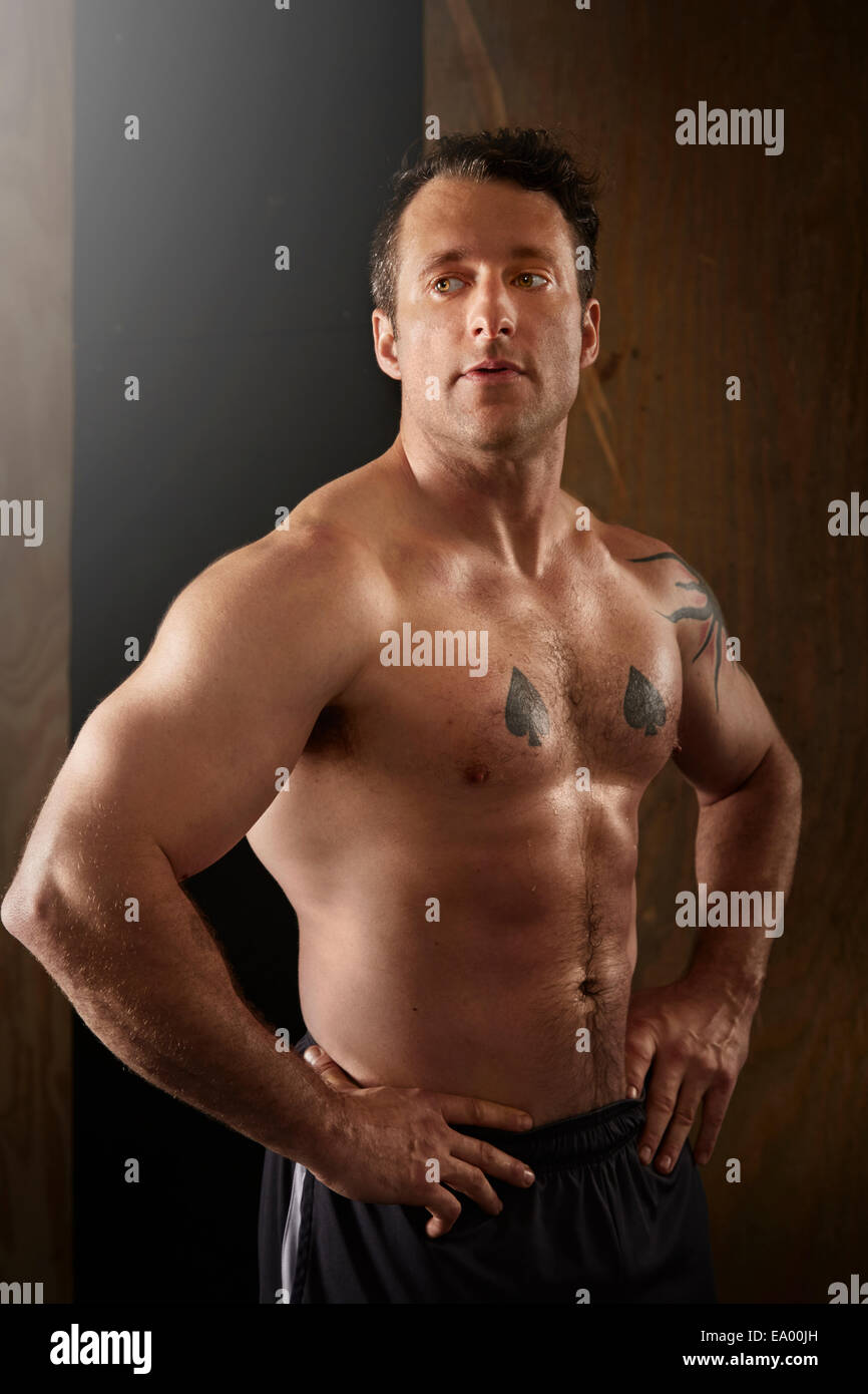 Muscular man posing in the gym with a towel on his shoulders