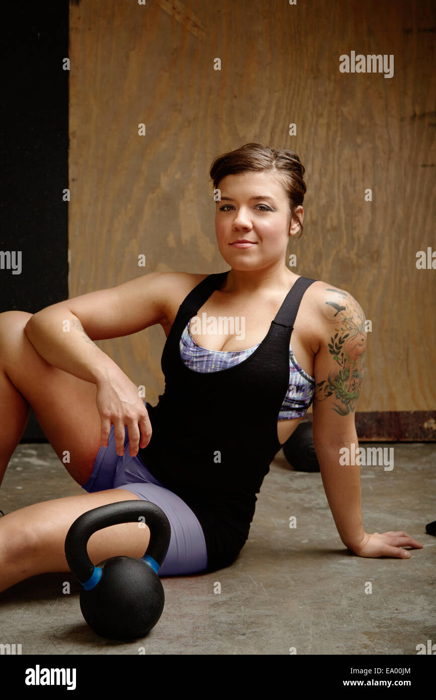 Portrait of young woman sitting on floor in gym Stock Photo
