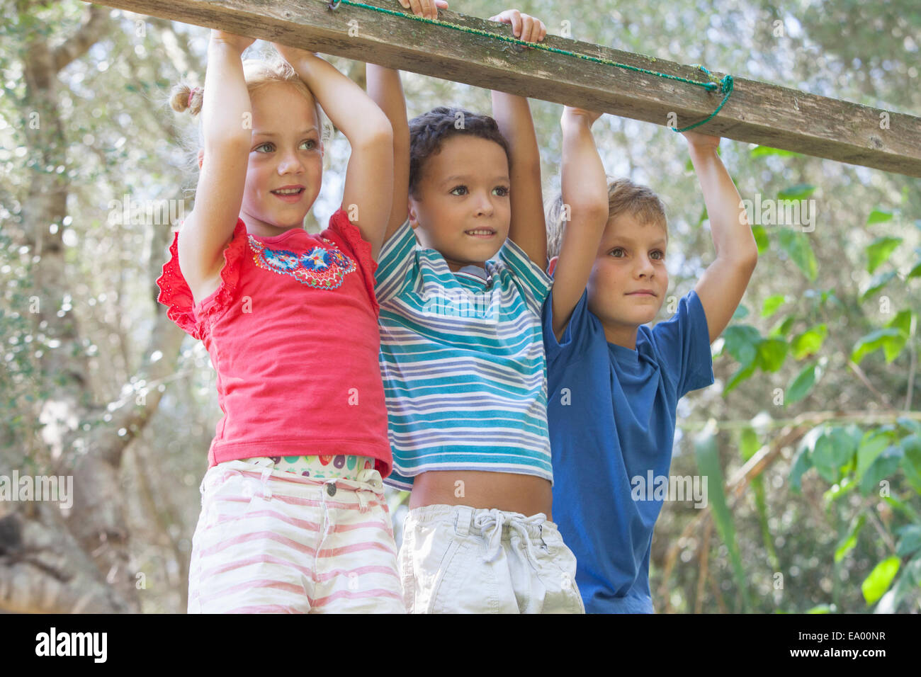 Three children holding onto fence looking away Stock Photo