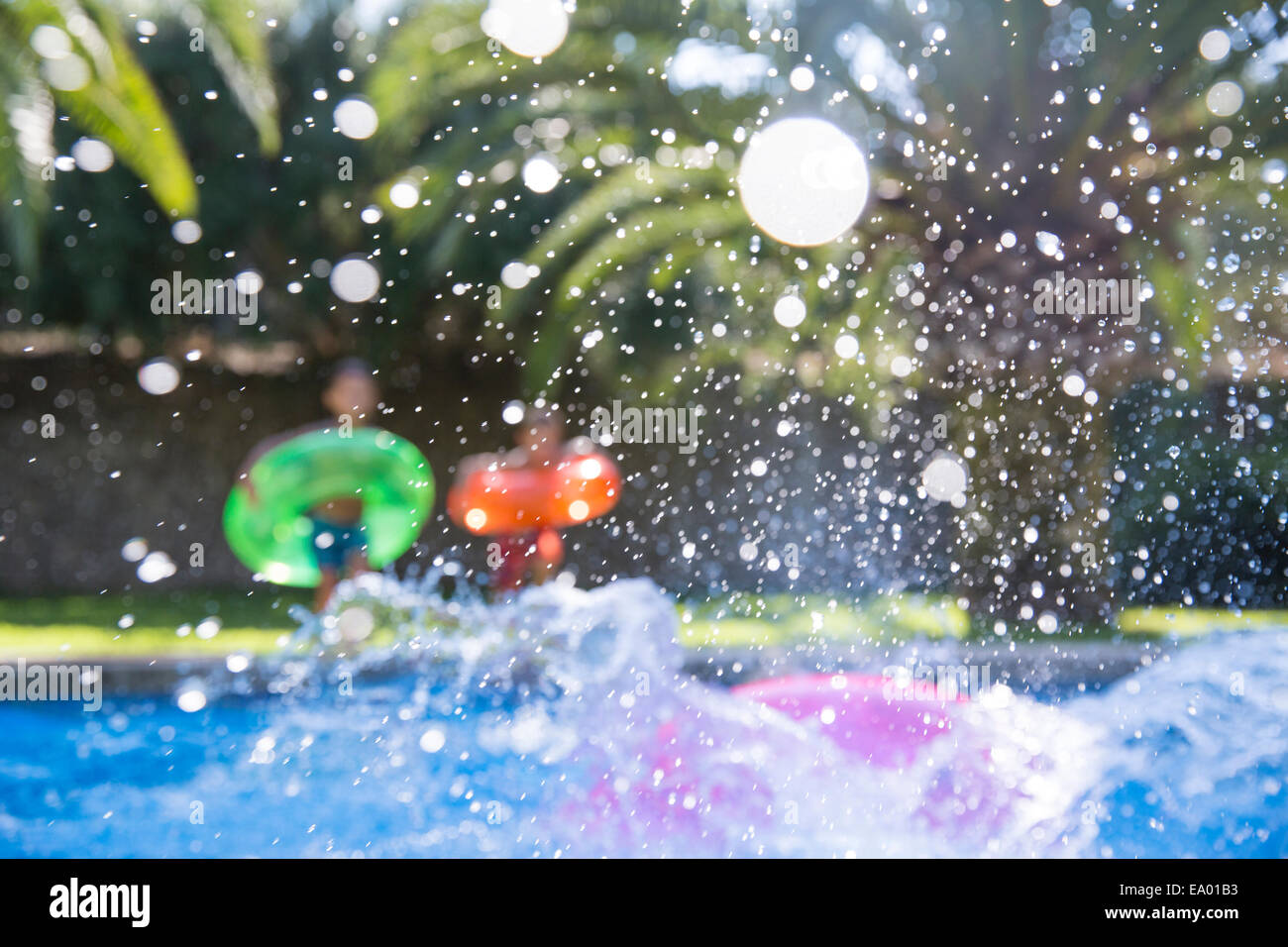 Three children making a splash in garden swimming pool Stock Photo