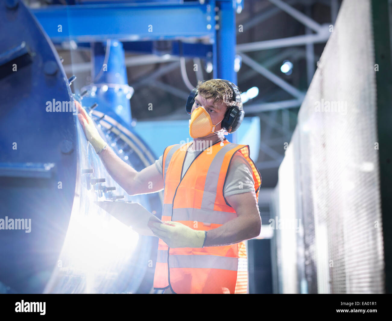 Worker checking metal ore grinding mill Stock Photo