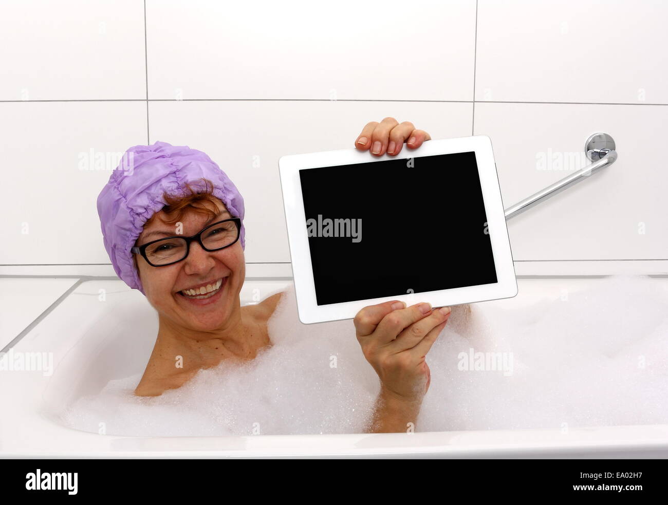 Enthusiastic mature woman in bathtub with tablet computers, close up Stock Photo