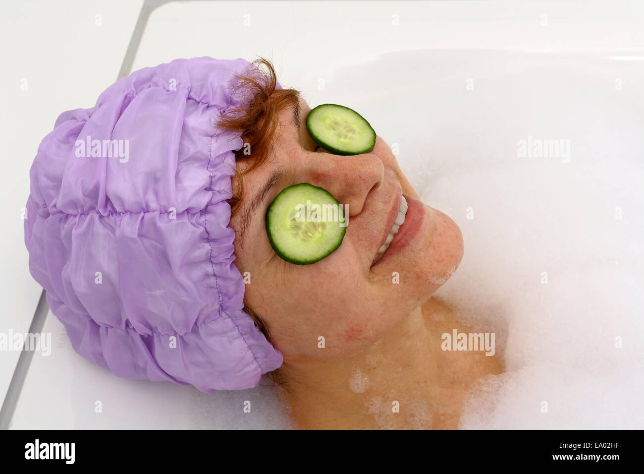 Mature woman in bathtub with cucumber slices on spectacle, spa procedure Stock Photo