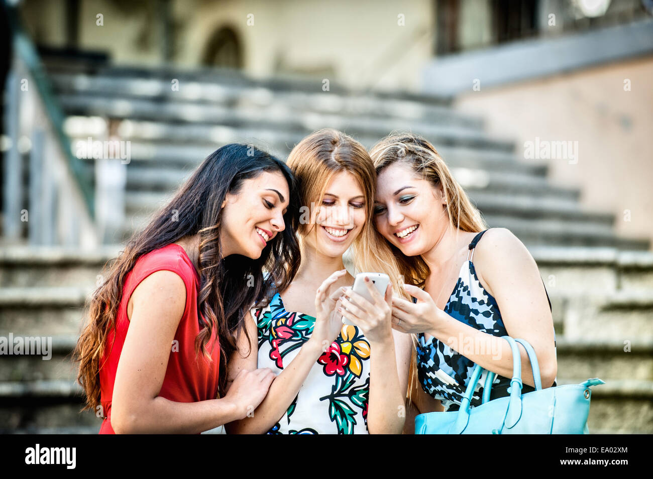 Three fashionable young women looking at smartphone, Cagliari, Sardinia, Italy Stock Photo