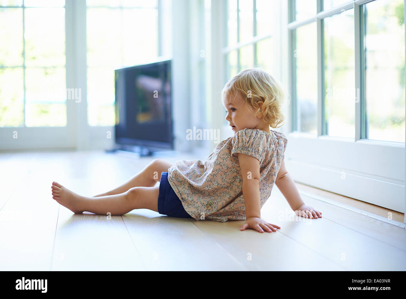 Portrait female toddler sitting on living room floor Stock Photo - Alamy