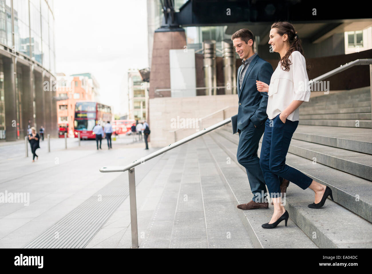 Rear view of young businessman and woman chatting whilst walking down stairway, London, UK Stock Photo