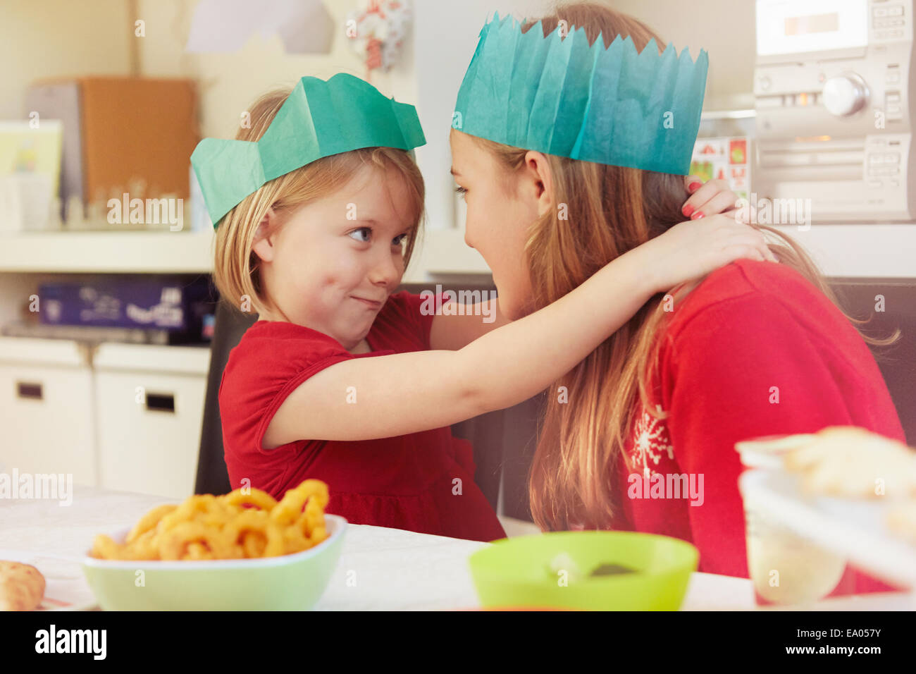 Sisters in paper crowns, hugging Stock Photo
