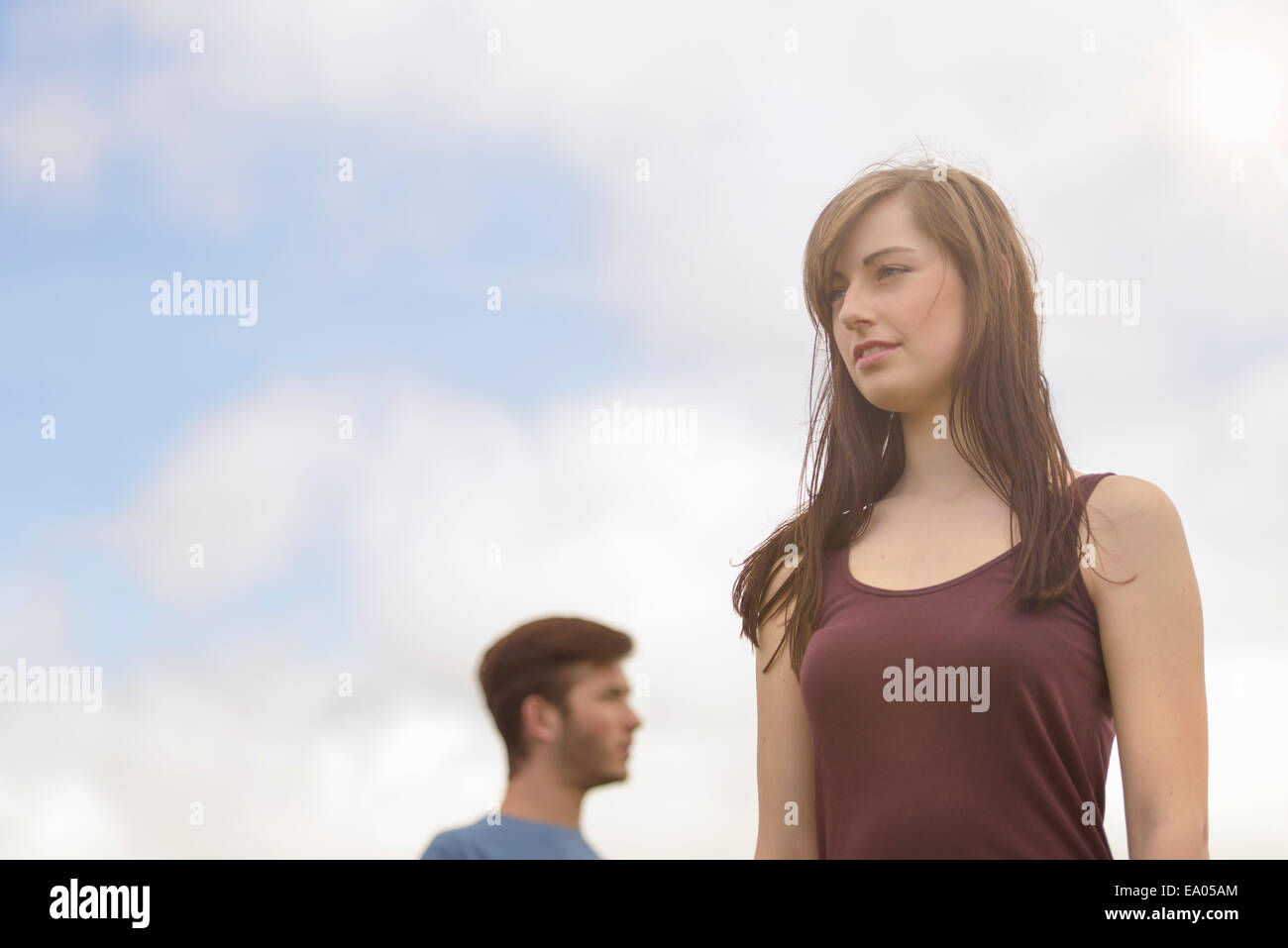 Young couple standing apart and looking away under bright blue sky Stock Photo